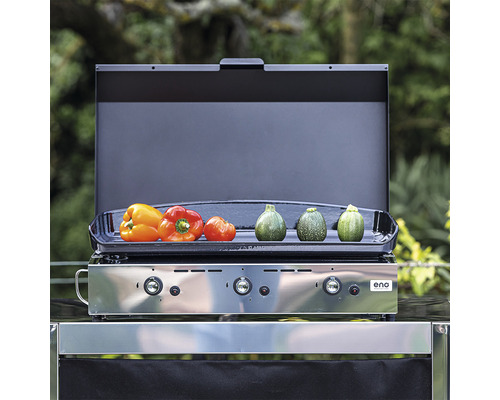 Grill à gaz avec des légumes comme des poivrons et des courgettes sur la surface de cuisson.