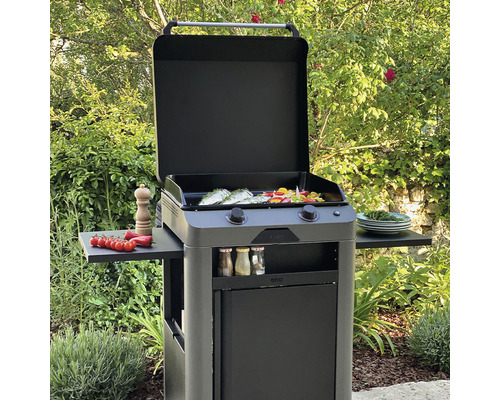 Grill avec capot ouvert et aliments sur la surface de cuisson dans le jardin