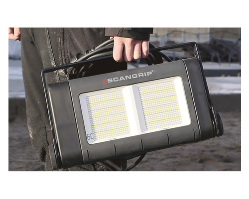 Une personne tient une lampe de travail Scangrip.
