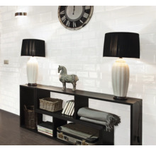 Wohnraum mit schwarzen Regalen, Tischlampen und weißen Wandfliesen im Retro-Stil