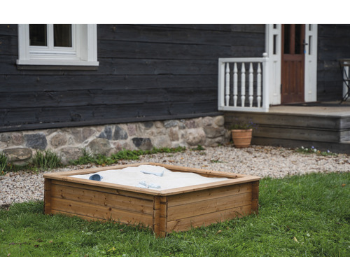 Bac à sable en bois dans le jardin avec sable et jouets