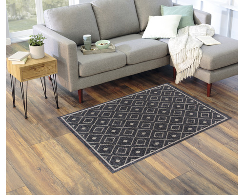 Wohnzimmer mit Sofa, Beistelltisch und einem Teppich mit Rautenmuster