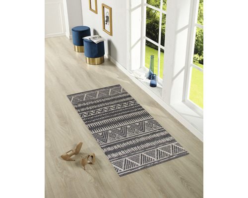 Raumansicht mit gemustertem Teppich, zwei Hockern und Dekoration