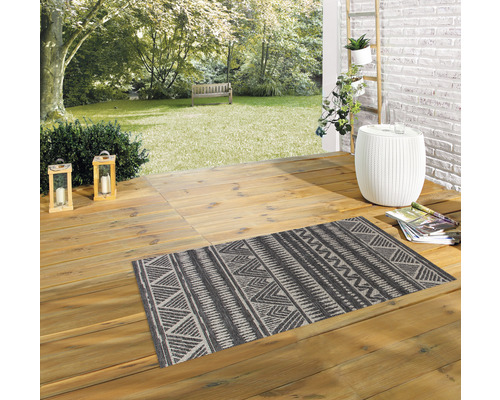 Szene mit einem gemusterten Teppich auf einer Holzterrasse in einem Garten.