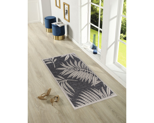 Innenaufnahme eines Raumes mit einem rechteckigen Teppich mit Blattmuster, zwei blauen Hockern und beigen Schuhen