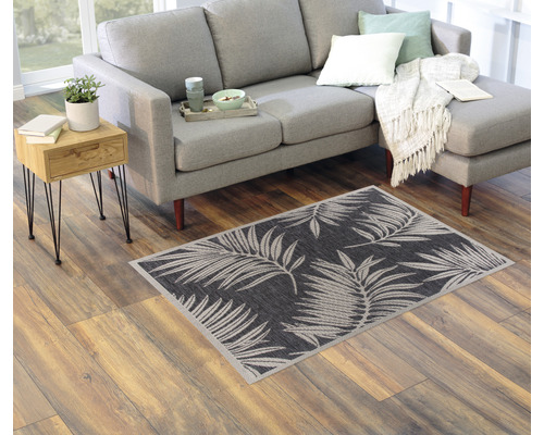 Wohnzimmer mit grauer Couch, Beistelltisch und Teppich mit Pflanzenmuster