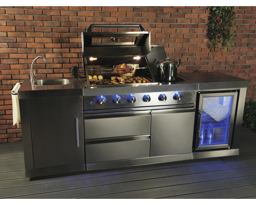 Cuisine extérieure en acier inoxydable avec évier, barbecue, réfrigérateur et espace de rangement devant un mur de briques