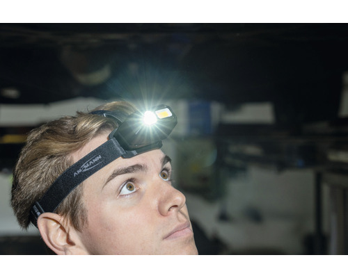 Une personne porte une lampe frontale Ansmann qui brille de mille feux.
