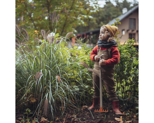 Enfant avec un râteau dans le jardin