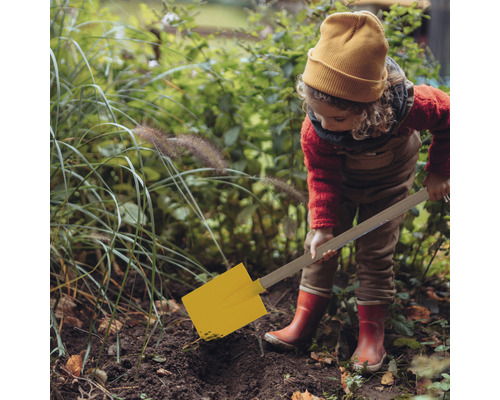 Enfant creusant dans le jardin avec une pelle jaune