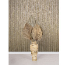 Feuilles de palmier séchées décoratives dans un vase en bambou devant un mur à motifs rayés.