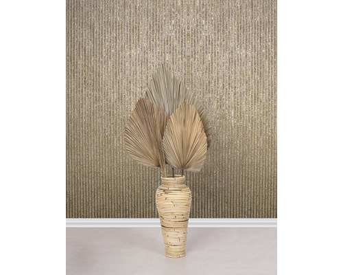 Feuilles de palmier séchées décoratives dans un vase en bambou devant un mur à motifs rayés.