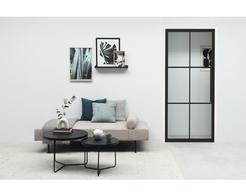 Salon avec lit de jour, tables basses, décoration murale et porte-fenêtre