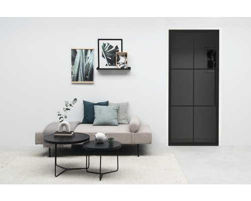 Salon avec canapé, tables basses, décoration murale et porte noire avec insert en verre