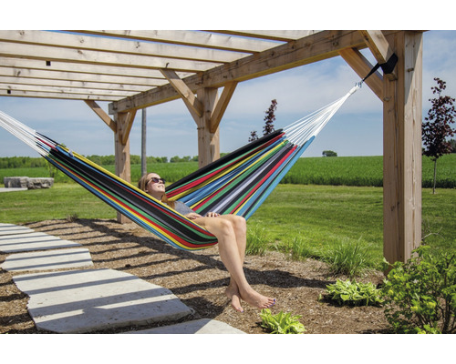 Frau entspannt in einer bunten Hängematte auf einer Holzterrasse