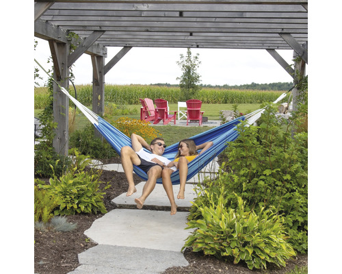 Ein Paar entspannt in einer blauen Hängematte unter einer Pergola im Garten.