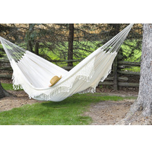 Hamac en tissu blanc avec bordure en crochet installé entre des arbres