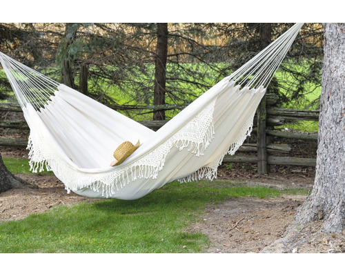 Hamac en tissu blanc avec bordure en crochet installé entre des arbres