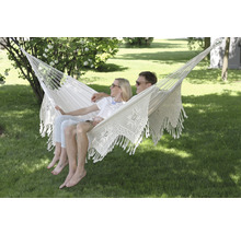 Couple se détendant dans un hamac blanc dans le jardin.