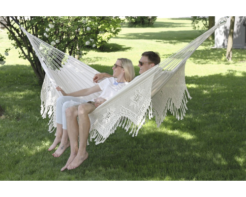 Couple se détendant dans un hamac blanc dans le jardin.