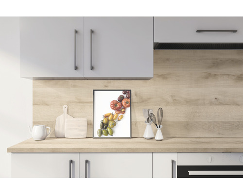 Cuisine lumineuse avec armoires de cuisine, plan de travail en décor bois, planches à découper, théière et image encadrée de différentes tomates