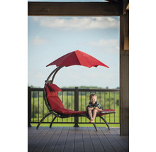 Garçon assis sur une chaise longue rouge avec parasol sur une terrasse