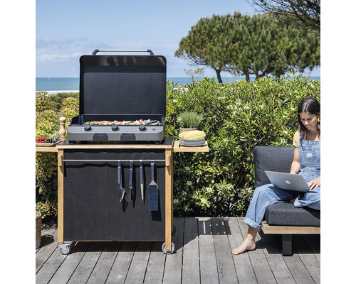 Scène extérieure avec chariot de grill, ustensiles de barbecue et personne avec ordinateur portable