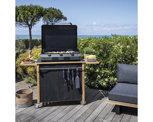 Chariot de grill avec couvercle ouvert, grillades et accessoires sur une terrasse en bois