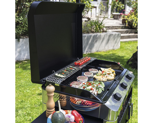 Barbecue à gaz avec légumes et viande sur la grille dans le jardin