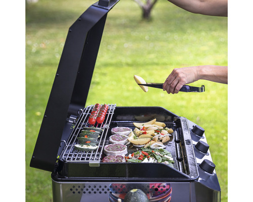 Une personne grille des légumes et de la viande sur un gril d''extérieur.