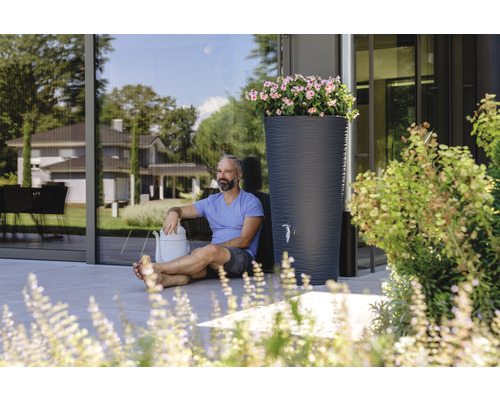 Szene mit Regentonne, Giesskanne und Mann im Garten