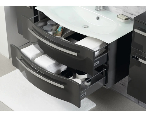 Badezimmerunterschrank mit offenen Schubladen, gefüllt mit Handtüchern und Pflegeprodukten.