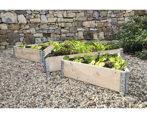 Trois potagers surélevés en bois avec ferrures métalliques dans le jardin.