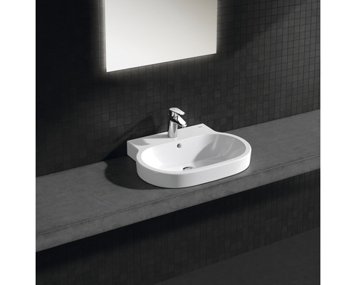 Lavabo avec robinet sur une étagère devant un mur sombre avec miroir