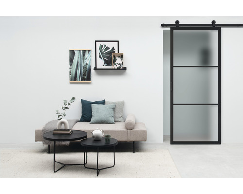 Salon avec porte coulissante, canapé, tables basses et décoration murale pour une ambiance élégante