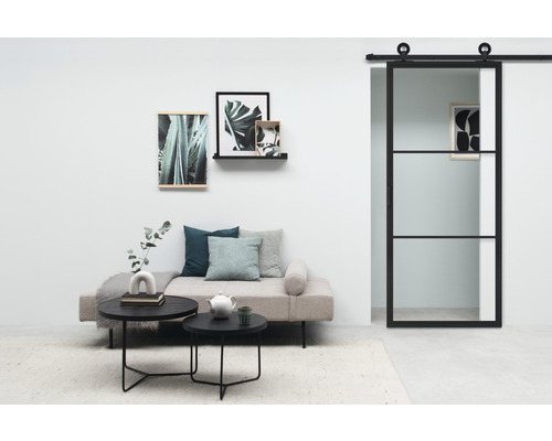 Pièce lumineuse avec canapé, tables basses, tableaux et porte coulissante en verre