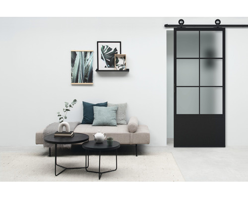 Salon avec porte coulissante, canapé, tables basses et décorations murales pour une atmosphère claire et organisée