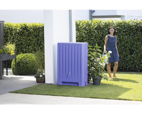 Szene mit einer Frau, die einen Garten mit einem Pflanzkasten und einem stehenden Wassertank giesst.