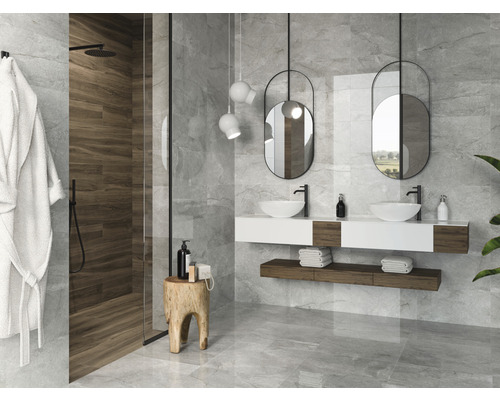 Salle de bain lumineuse avec douche, double vasque, miroir et carrelage gris.