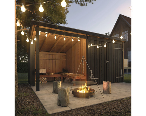 Scène avec remise à bois, foyer et guirlande lumineuse dans le jardin