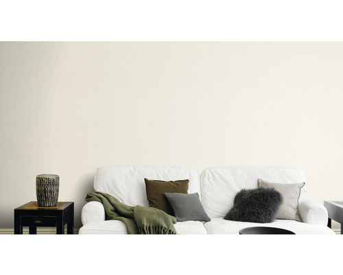 Salon avec canapé blanc, coussins et table d''appoint devant un mur