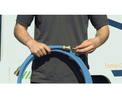 Une personne raccorde un raccord rapide à un tuyau d''arrosage