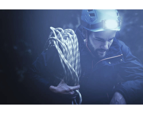 Homme avec corde d''escalade et lampe frontale