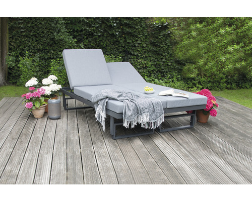 Double chaise longue en métal avec coussin et couverture dans le jardin sur une terrasse en bois