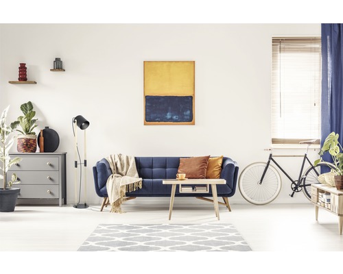 Wohnzimmer mit blauem Sofa, Couchtisch, Kommode, Stehlampe und Kunstwerk an der Wand.