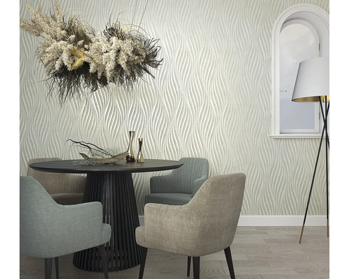 Salle à manger avec table ronde, chaises, décoration florale, lampadaire et papier peint à motif ondulé.