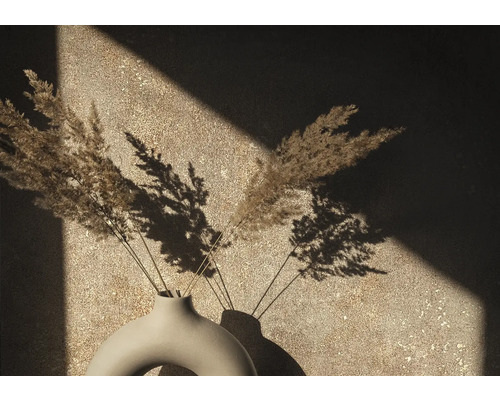 Dekorative Vase mit getrockneten Gräsern vor einer Wand