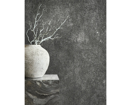 Gros plan d''un vase avec des branches devant un mur texturé sombre