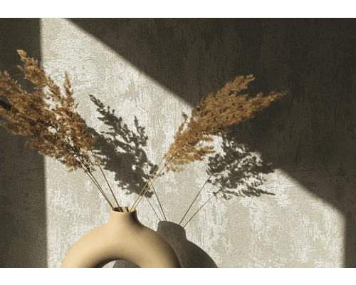 Fleurs séchées décoratives dans un vase en céramique devant un mur avec des ombres portées
