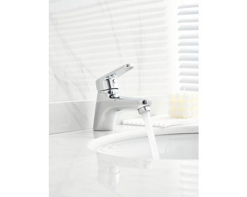 Robinet chromé avec de l''eau qui coule dans un lavabo de salle de bain.